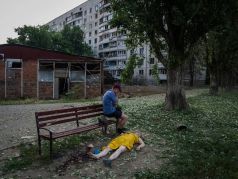 Житель Харькова у тела женщины, погибшей в результате обстрела города. Фото: Evgeniy Maloletka / AP